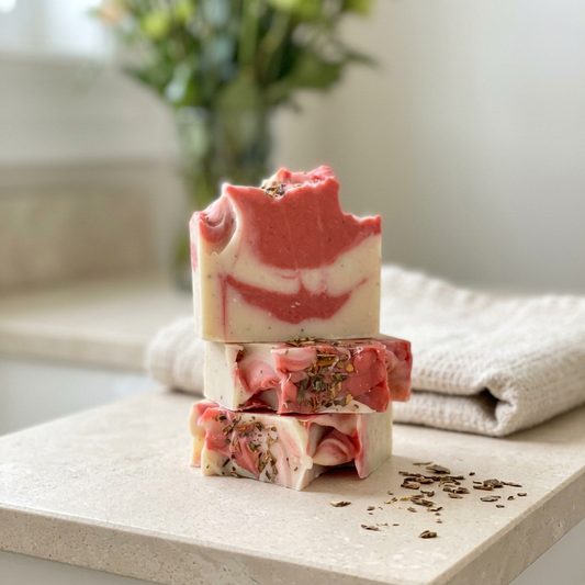 Boat Deck coral and ivory swirled soap bars stacked on a bathroom counter beside a folded towel