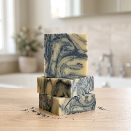 Three stacked charcoal and creamy yellow Turmeric Swirl soap bars
